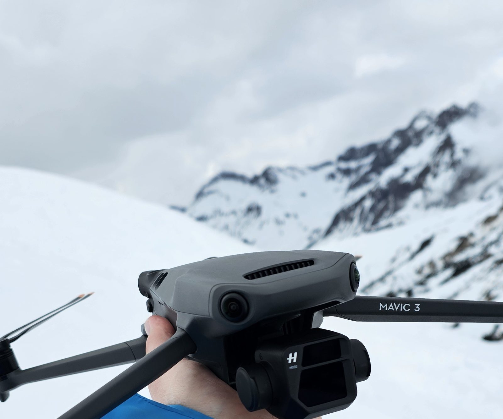 DJI Mavic 3 in der Hand vor verschneiten Bergen